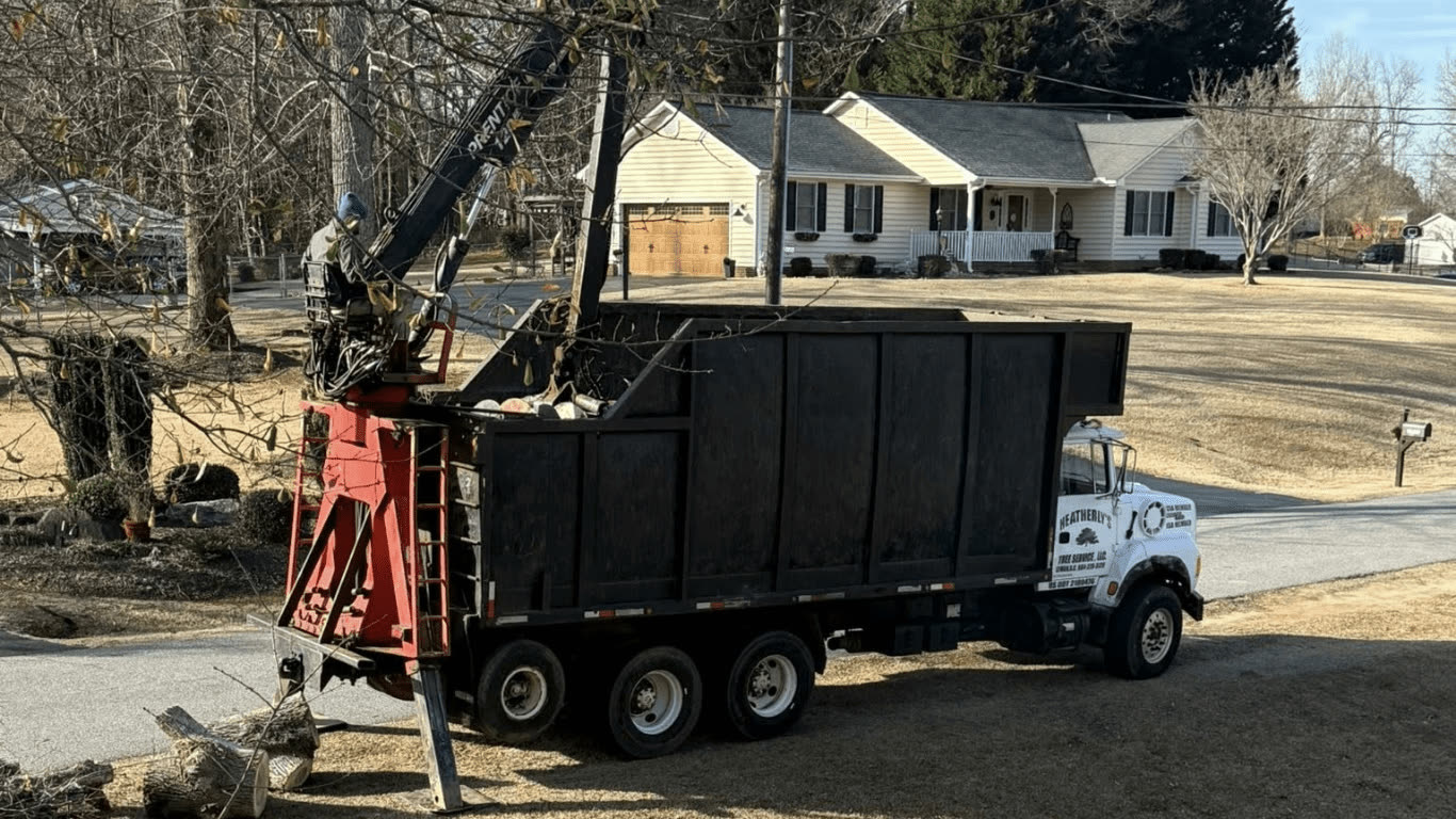 The grapple truck loading out beside the house.